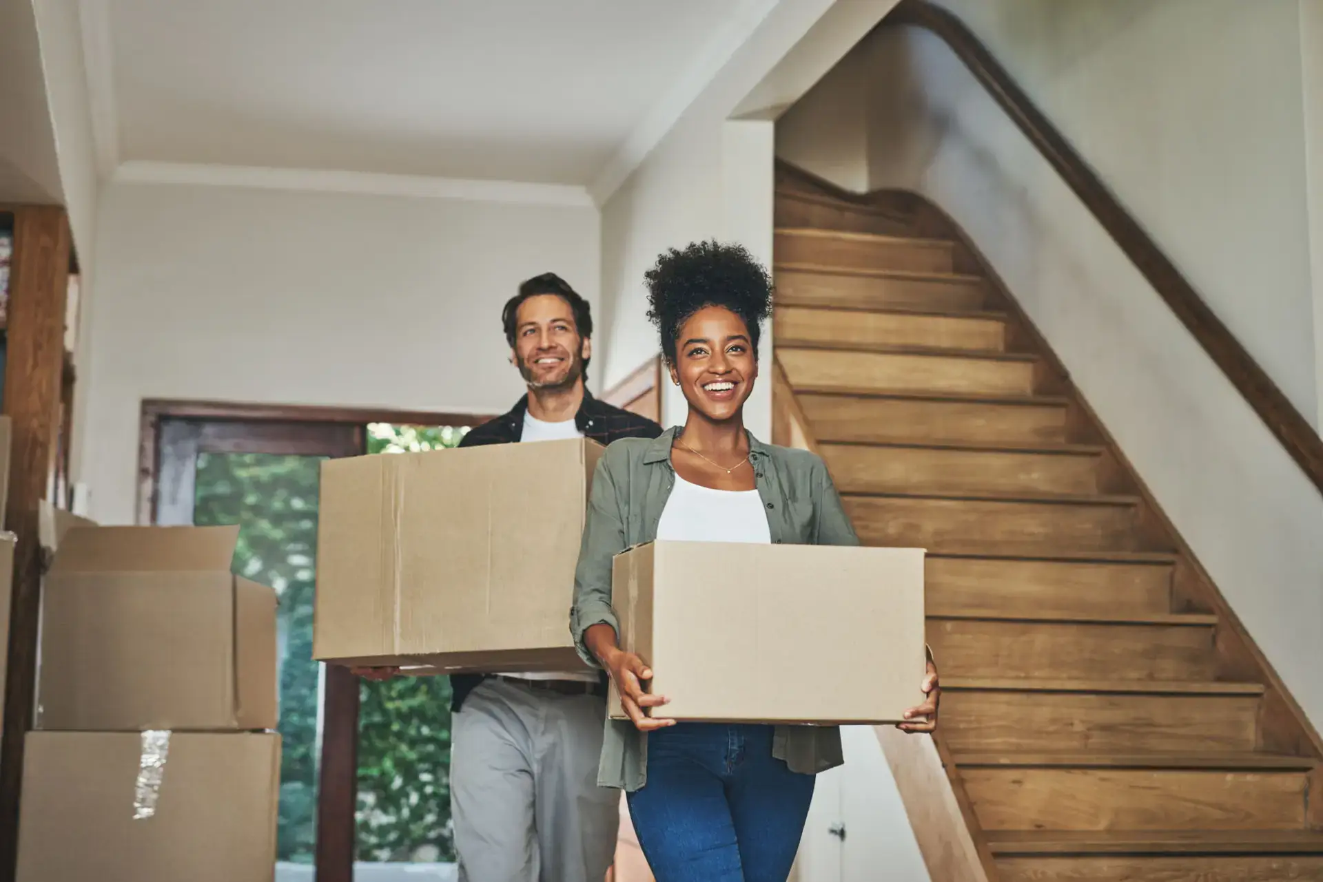 Happy first-time homebuyers carrying moving boxes into their new home